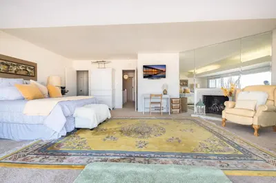 a bedroom with a bed and a living room with a fireplace at Spacious 3Br Bayfront W Harbor Views, Walk To Beach By Beachview Rentals in Newport Beach
