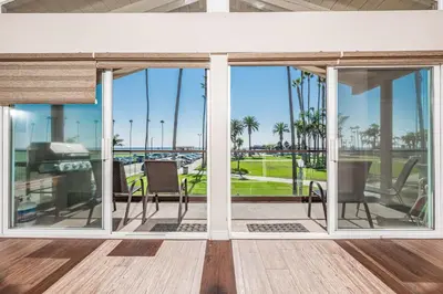 a screened porch with chairs and a view of the ocean at 3Br Oceanfront At Balboa Pier W Ac And Great Walkability By Beachview Rentals in Newport Beach