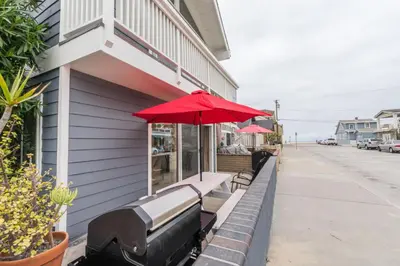 a red umbrella sitting on the side of a building at 5Br Coastal Retreat W Ocean Views - Steps From Beach By Beachview Rentals in Newport Beach