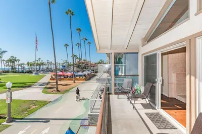 a balcony with a view of the beach and palm trees at 6Br Oceanfront Duplex, Ac, Steps To Beach And Balboa Pier By Beachview Rentals in Newport Beach