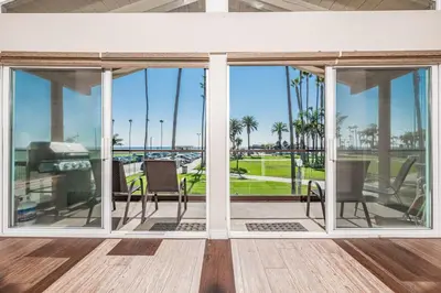 a screened porch with chairs and a view of the ocean at 6Br Oceanfront Duplex, Ac, Steps To Beach And Balboa Pier By Beachview Rentals in Newport Beach