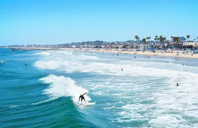 a person riding a wave on a surfboard in the ocean at Luxe 3Br Near The Sand W Rooftop Spa, Ocean Views, And Ac By Beachview Rentals in Newport Beach