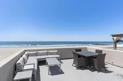 a patio with a table and chairs and the beach at Elegant 6Br Oceanfront W Rooftop Deck And Stunning Views By Beachview Rentals in Newport Beach