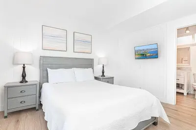 a white bedroom with a white bed and two night stands at Cozy And Central 3Br, Steps From Sand And Marina Park By Beachview Rentals in Newport Beach