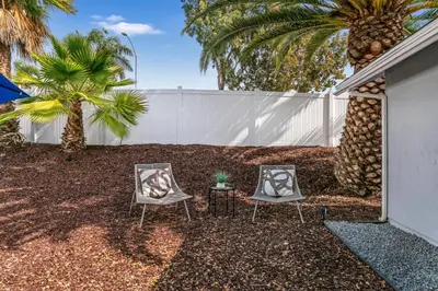 two chairs and a table in a yard with palm trees at Neat Retreat w Hot Tub Near Beach and Downtown in San Diego