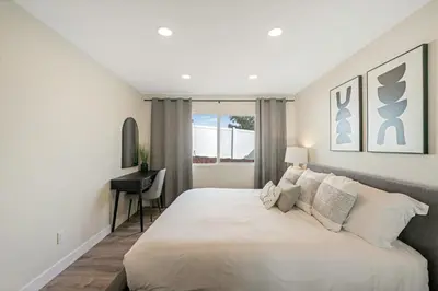 a bedroom with a large white bed and a desk at Neat Retreat w Hot Tub Near Beach and Downtown in San Diego