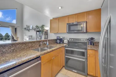 a kitchen with wooden cabinets and stainless steel appliances at Point Loma 2BR Townhome w Parking in Prime Location in San Diego