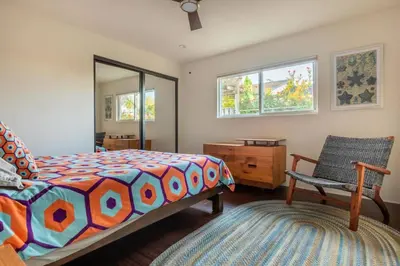 a bedroom with a bed and a chair and a mirror at San Diego Staycation Home with Hot Tub Ocean Views in Encinitas