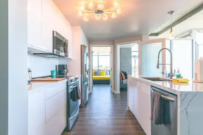 a kitchen with white cabinets and a ceiling fan at Modern Downtown SD Apartment Stunning City Views in San Diego