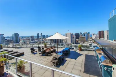 a patio with chairs and an umbrella on top of a building at Modern Downtown SD Apartment Stunning City Views in San Diego
