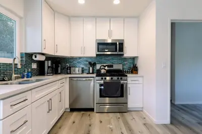 a kitchen with white cabinets and stainless steel appliances at Staycation Beach Family Home Great Indoor Outdoor in Carlsbad