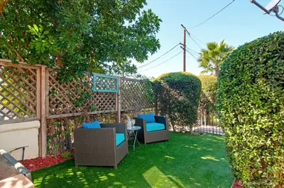 a backyard with two chairs and a table and a fence at Cute Old Town Cottage near Downtown Beaches in San Diego