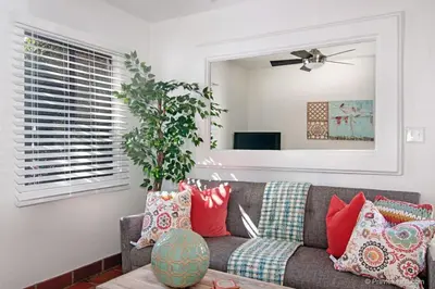 a living room with a gray couch with red pillows at Cute Old Town Cottage near Downtown Beaches in San Diego