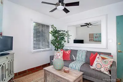 a living room with a couch and a ceiling fan at Cute Old Town Cottage near Downtown Beaches in San Diego