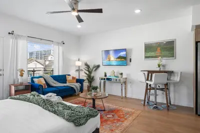 a living room with a bed and a blue couch at Stylish Top-Floor Gem with King Bed & City Ocean Views in San Diego
