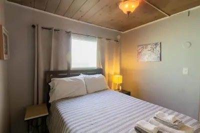a bedroom with a bed with white sheets and a window at Cozy Ocean Beach Cottage Separate Entry in San Diego