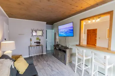 a living room with a couch and a tv on the wall at Cozy Ocean Beach Cottage Separate Entry in San Diego