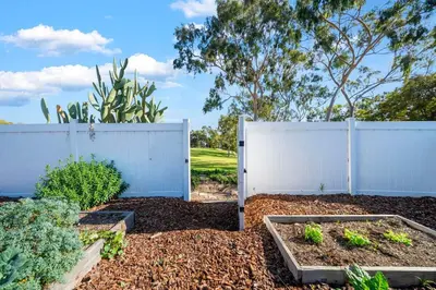 a white fence in a garden with some plants at Decked Out Delight Park Charm in San Diego