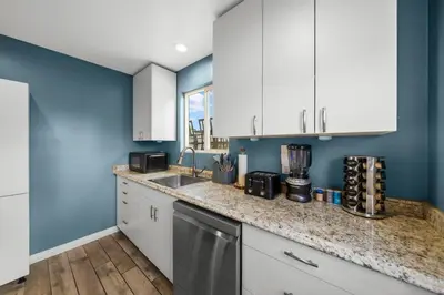 a kitchen with blue walls and white cabinets at Decked Out Delight Park Charm in San Diego