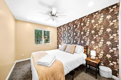 a bedroom with a bed with a floral accent wall at Decked Out Delight Park Charm in San Diego