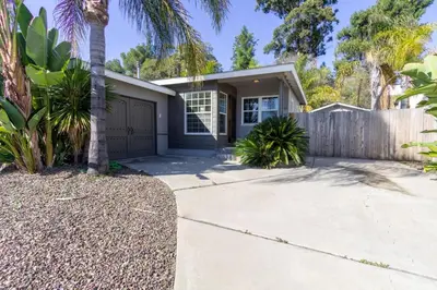a house with a palm tree in front of a driveway at Centrally Located Cottage Near Lake Trails Shops in La Mesa