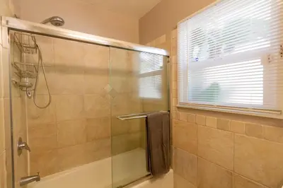 a bathroom with a shower with a glass door at Centrally Located Cottage Near Lake Trails Shops in La Mesa