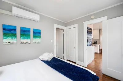 a white bedroom with a bed and a blue rug at The Captain Quarters- Rosecrans Marina Escape in San Diego