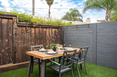 a wooden table and chairs in a backyard with a fence at The Captain Quarters- Rosecrans Marina Escape in San Diego