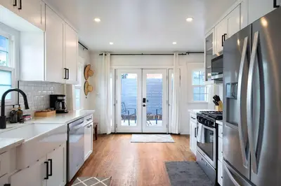 a kitchen with white cabinets and a stainless steel refrigerator at The Captain Quarters- Rosecrans Marina Escape in San Diego