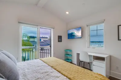 a bedroom with a bed and a desk and windows at Bayside Cove 10 in San Diego