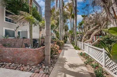 a sidewalk in front of a house with palm trees at Seaside Retreat in San Diego