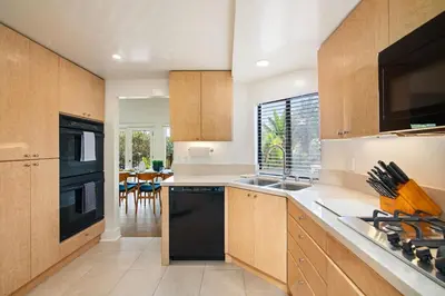 a kitchen with wooden cabinets and a black dishwasher at La Jolla Hillside Views and Coastal Comfort in San Diego