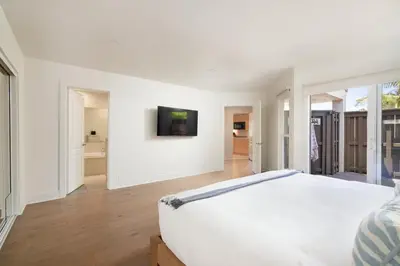 a white bedroom with a bed and a tv on a wall at La Jolla Hillside Views and Coastal Comfort in San Diego