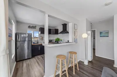 a kitchen with a refrigerator and two bar stools at Charming Gem in LH, High Speed WiFi Minutes from Beach, Downtown & Petco Park! in San Diego