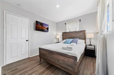 a bedroom with a large bed with a wooden headboard at Charming Gem in LH, High Speed WiFi Minutes from Beach, Downtown & Petco Park! in San Diego