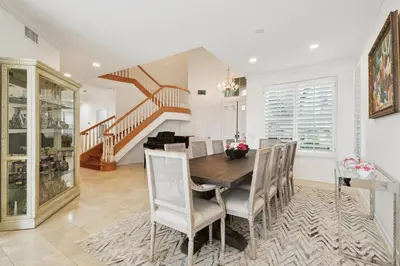 a dining room with a table and chairs and a staircase at Exquisite Panoramic View Estate in Newport Beach