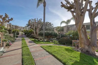 a walkway in a park with palm trees at Aqua Luxe - SUR113 in Solana Beach