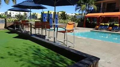 a group of chairs and tables with umbrellas next to a pool at Vive Luxe in San Diego
