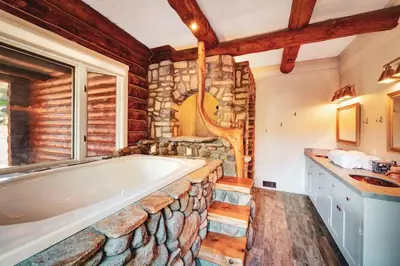 a bathroom with a large tub and a stone wall at Red Hawk Ridge SD Mag Design Winner in Alpine