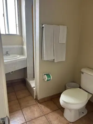 a bathroom with a toilet and a sink with towels at Star Motel in San Diego