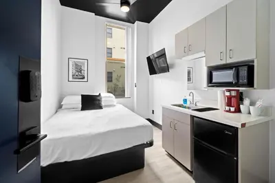 a small bedroom with a bed and a kitchen at The Neon Elm Hotel in San Diego