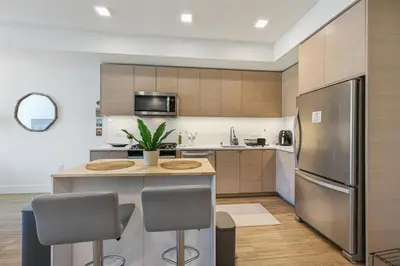 a kitchen with a refrigerator and a table with chairs at NEW Upscale Downtown San Diego Stay Queen Bed Pool & Sauna in San Diego