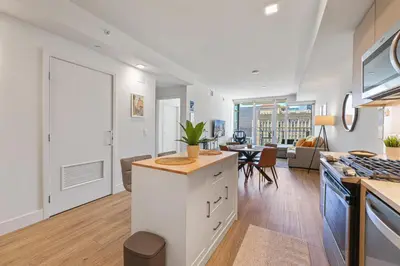 a kitchen with white cabinets and a living room at NEW Upscale Downtown San Diego Stay Queen Bed Pool & Sauna in San Diego