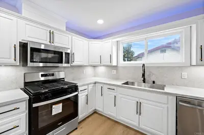 a kitchen with white cabinets and a stove and a sink at Xlnc Exotic home Poway in Poway