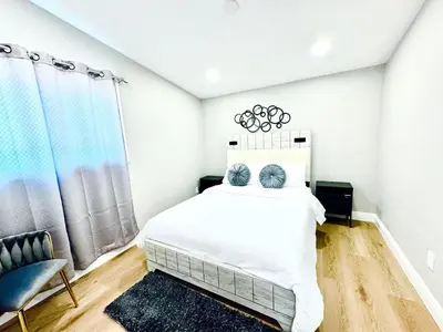 a white bedroom with a bed and a chair at Xlnc Exotic home Poway in Poway