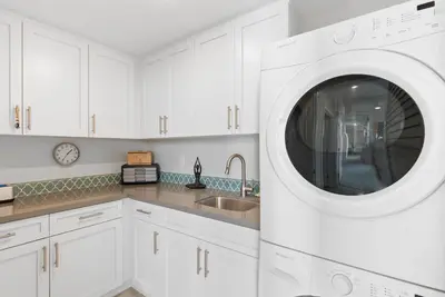 a white kitchen with a sink and a washing machine at The Penthouse Oceanfront in Oceanside