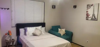 a bedroom with a bed and a green chair at Galaxy House in Sun City