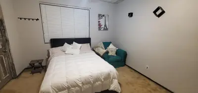 a bedroom with a bed and a green chair at Galaxy House in Sun City