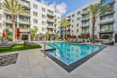 a swimming pool in front of a building with palm trees at Global Luxury Suites Mission Valley East in San Diego