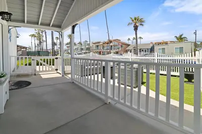 a porch with a white fence and palm trees at Luxury Oceanfront steps to Beach & Town, Best views! in Oceanside